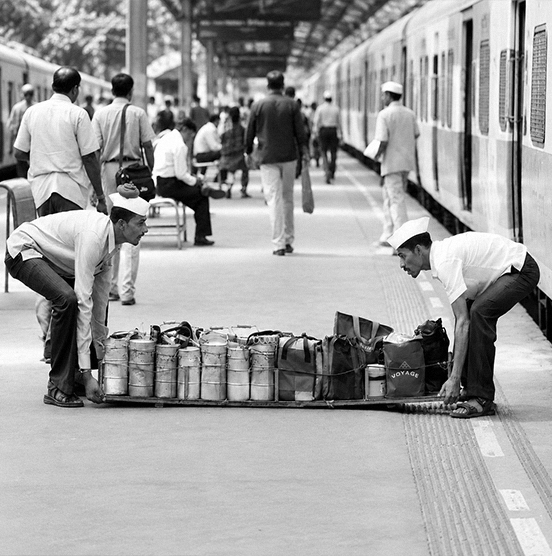 Dabbawalas loading tiffin carriers at a Mumbai train platform, historical photo
