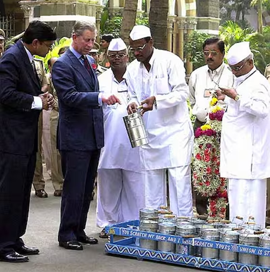 A dabbawala presenting a tiffin carrier to a visiting dignitary, historical photo